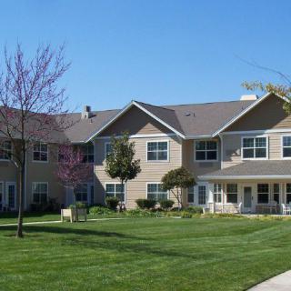 A two-story residential building with a well-maintained lawn and clear blue sky.