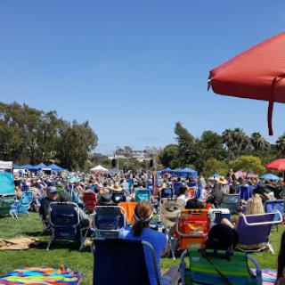 A lively outdoor event with a large crowd enjoying the sunny weather.