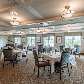 An elegantly decorated dining room with neatly arranged tables and chairs, illuminated by warm lighting.