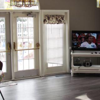 A cozy living room featuring a television, large windows, and stylish furniture.