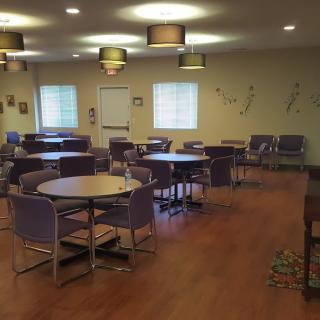Empty dining area with neatly arranged tables and chairs, featuring modern lighting.