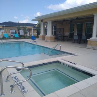 Outdoor swimming pool and hot tub area with adjacent patio seating.