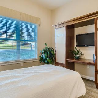 A cozy bedroom featuring a comfortable bed, natural light from a window, and stylish wooden furnishings.