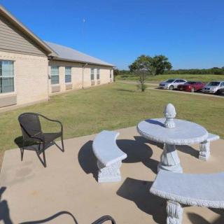 A patio with stone furniture and a view of a grassy area next to a building.