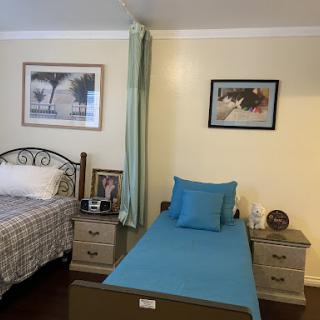 A cozy bedroom featuring two beds, decorative artwork, and stylish furnishings.