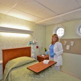 A nurse standing beside a bed in a hospital room equipped with medical facilities.