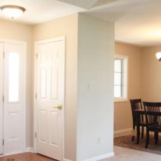A well-lit entryway leading into a dining area with furniture and windows.