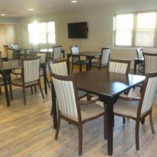 A spacious dining area with multiple tables and chairs, featuring a TV on the wall.