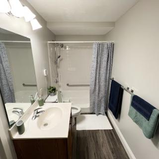 A modern bathroom featuring a sink, shower, and neatly arranged towels.