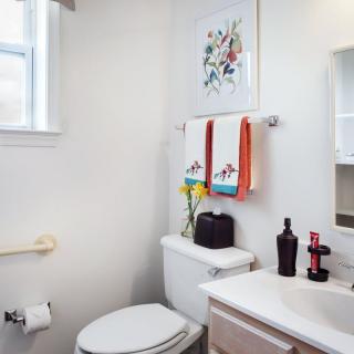 A small, tidy bathroom with colorful towels, wall art, and simple decor.