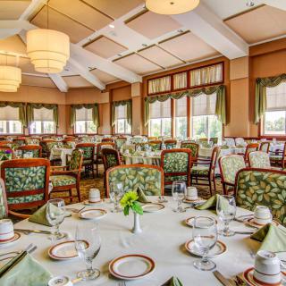 An elegant restaurant dining room with beautifully set tables and ornate chairs.