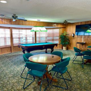A cozy game room featuring a pool table and seating area adorned with green chairs and hanging lights.