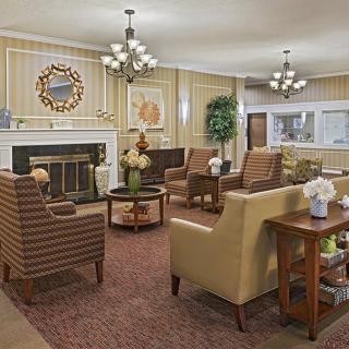 A cozy living room with comfortable seating, a fireplace, and elegant chandeliers.