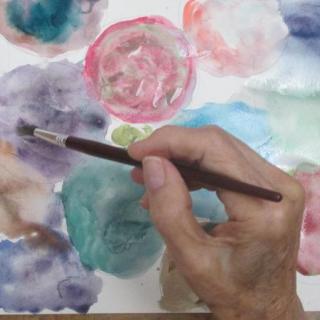 A person painting with watercolors, using a brush to create colorful abstract patterns.