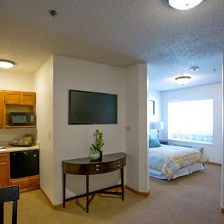 A modern studio apartment with a kitchenette and cozy bedroom area.