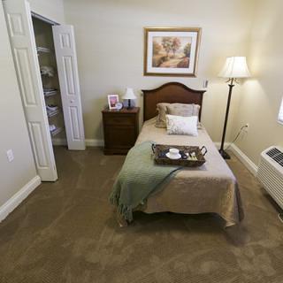 A cozy bedroom with a single bed, nightstand, and lamp.