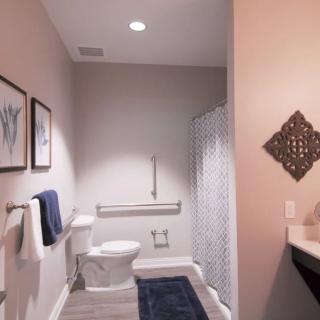 A modern bathroom featuring a toilet, shower with curtain, and tasteful decor including towels and wall art.