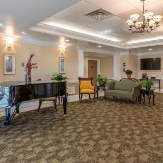 A well-decorated lobby with a grand piano, comfortable seating, and elegant lighting.