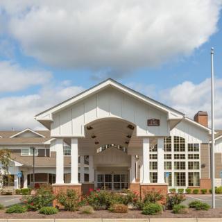 A large building with a prominent entrance and cloudy sky in the background.