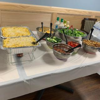 A selection of dishes at a buffet setup, featuring salads and a cheesy casserole.