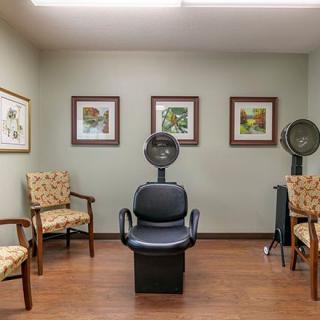 A cozy salon interior with chairs and hair dryers, adorned with framed artwork on the walls.