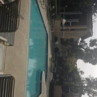 Outdoor swimming pool with surrounding patio and chairs.