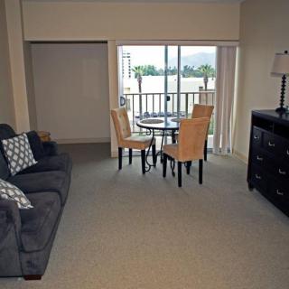 A cozy living room with a dining area, featuring a sofa, chairs, table, and access to a balcony.