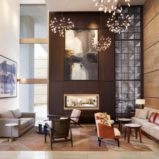 A modern and luxurious lobby featuring stylish furniture, a central fireplace, and large artwork adorning the walls.