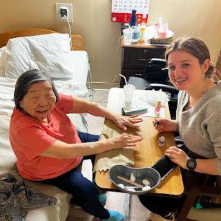 A caregiver and an elderly resident enjoy a creative moment together, showcasing the joy of companionship in a nursing home.