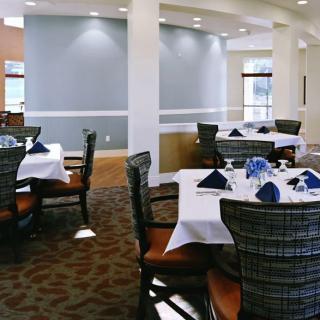A neatly arranged dining area in a restaurant with blue napkins and elegantly set tables.