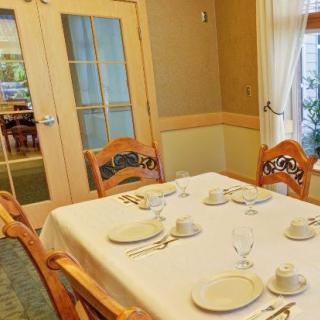 A dining room with a neatly set table featuring a white tablecloth, plates, glasses, and silverware.