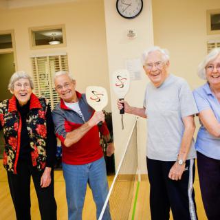 A group of seniors enjoying a game of pickleball indoors.