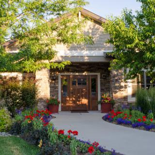 A charming house surrounded by vibrant flowers and lush greenery, illuminated by warm sunlight.
