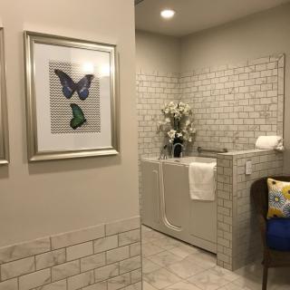 A modern bathroom with a bathtub, tiled walls, and butterfly artwork.