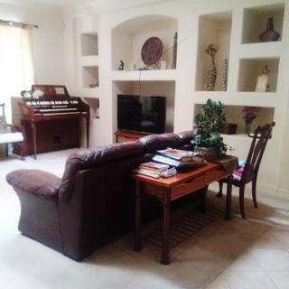Cozy living room featuring a sofa, a wooden table, and shelves displaying decorative items.