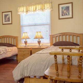 A cozy bedroom featuring two twin beds, wooden furniture, and softly glowing lamps.