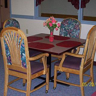 A cozy dining area with a table, four chairs, and a floral centerpiece.