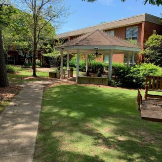 A peaceful garden with a gazebo and surrounding greenery on a sunny day.