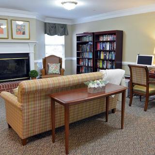 Cozy living room with a sofa, armchair, fireplace, bookshelf, and computer desk.