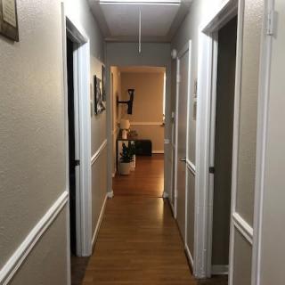 A well-lit hallway with wooden flooring and several doors on either side.