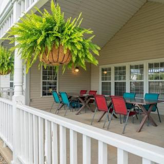 A cozy covered porch with colorful chairs and a table, adorned with hanging plants.