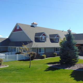 A suburban house with a well-maintained lawn and trees under a clear blue sky.