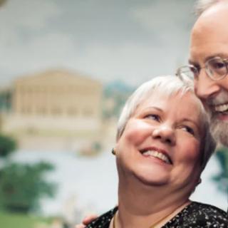 A senior couple smiling warmly outdoors, showcasing their affection for each other.