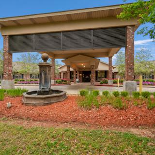 A welcoming entrance featuring a fountain and landscaped garden under a clear blue sky.