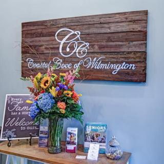 A beautifully decorated reception area with a wooden sign and a vibrant bouquet of flowers.
