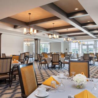 An elegant dining room with neatly arranged tables and chairs, featuring chandeliers and a sophisticated interior design.