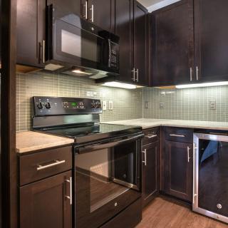 A modern kitchen featuring dark wood cabinets, stainless steel appliances, and a tile backsplash.