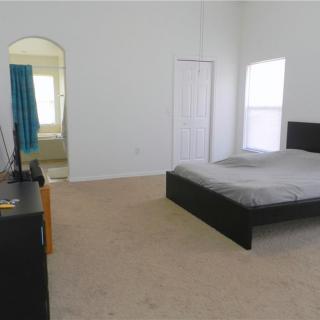 A minimalist bedroom with a bed, dresser, and carpeted floor.