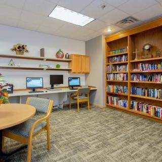 A quiet library corner with bookshelves, computers, and a table with chairs.