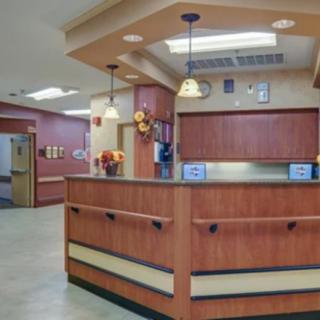 A clean and organized hospital reception area with a wooden front desk and overhead lighting.
